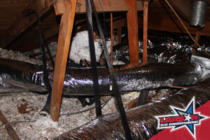 An HVAC technician working on ductwork and insulation in an attic for Larson Air Conditioning in Scottsdale, AZ