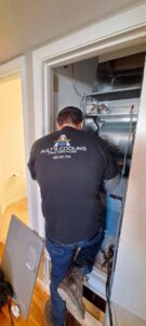 An HVAC technician from Ault's Cooling HVAC Services LLC working on an indoor furnace or air handler unit in Chandler, AZ.