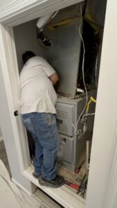 An HVAC technician working on an indoor furnace and air handler unit for Bluestone Refrigeration LLC in Las Cruces, NM.