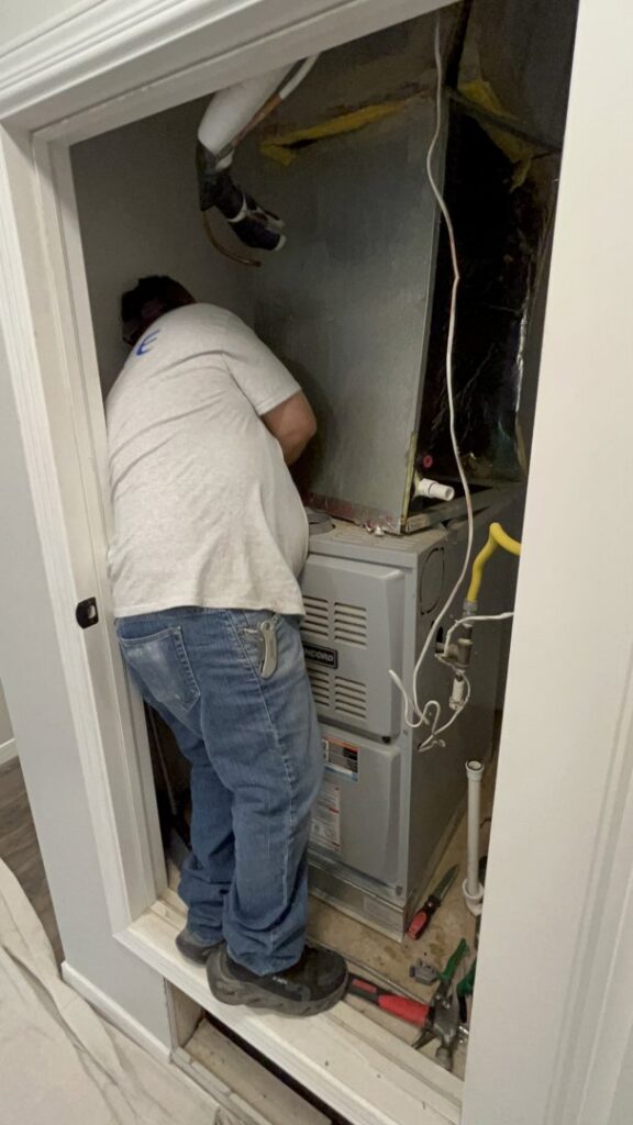 An HVAC technician working on an indoor furnace and air handler unit for Bluestone Refrigeration LLC in Las Cruces, NM.
