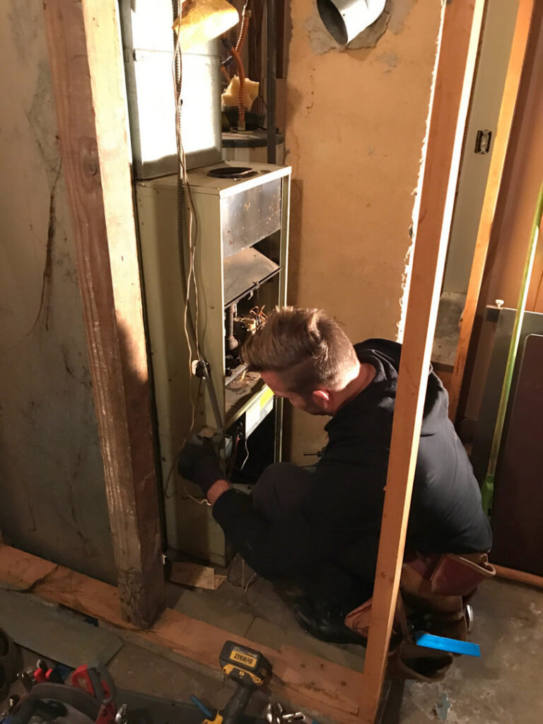 An HVAC technician from Columbia Heating & Air Conditioning working on a furnace unit in Kent, WA.