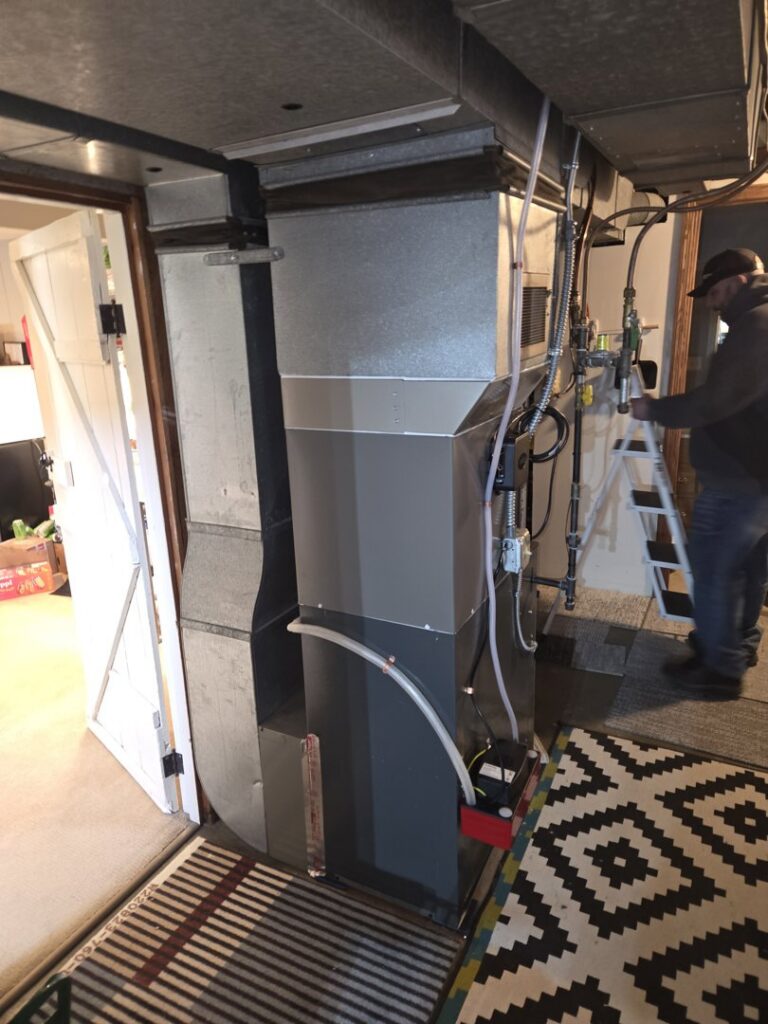 An HVAC technician working on a furnace unit, performing service or installation for Cyber Heating and Cooling in Bloomington, MN.