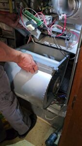 An HVAC technician working on the internal components of a furnace or air handler for Ecology Air Innovations in Sacramento, CA.