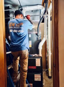 An HVAC technician working on a furnace unit for Ideal Heating & Air Conditioning in Omaha, NE.