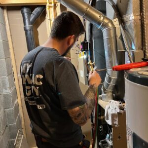 An HVAC technician from My HVAC Guy performing service on a furnace system in a basement in North Canton, OH.