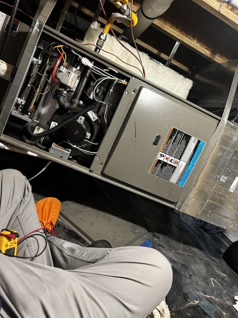 An HVAC technician working on an open furnace, performing service or repair for Waymaker HVAC LLC in Colorado Springs, CO.