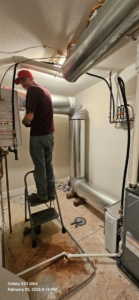 An HVAC technician working on a furnace and ductwork system for Strategic Heating and Cooling in South Boston, VA.