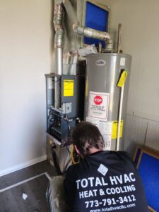 An HVAC technician from Total HVAC - Heating and Cooling working on a furnace and water heater in Nashville, TN.