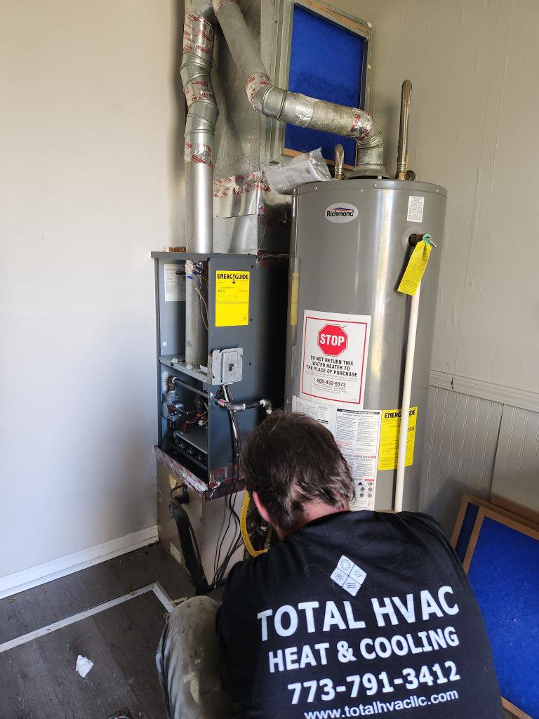 An HVAC technician from Total HVAC - Heating and Cooling working on a furnace and water heater in Nashville, TN.