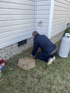 An HVAC technician from Sturdi Home Solutions working on an outdoor gas line connection near a house in Chattanooga, TN.