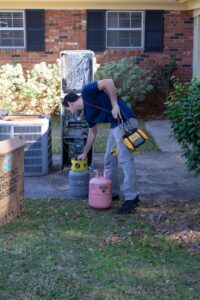 An HVAC technician from Coral Air Conditioning working on an outdoor AC unit with refrigerant tanks in Cape Coral, FL.