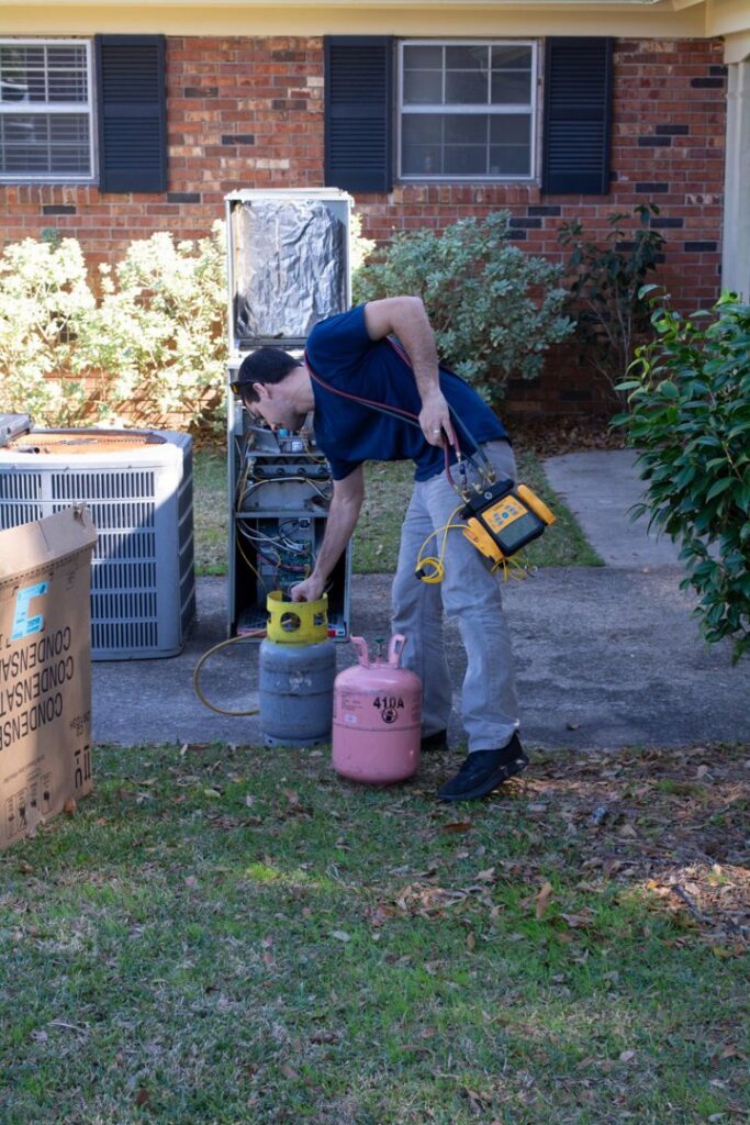 An HVAC technician from Coral Air Conditioning working on an outdoor AC unit with refrigerant tanks in Cape Coral, FL.