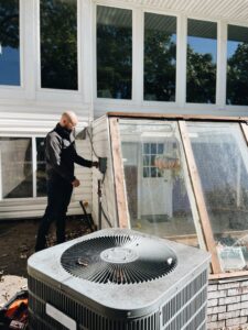 An HVAC technician from Davis Heating, Air Conditioning & Home working on an outdoor AC condenser unit at a residence in Overland Park, KS.