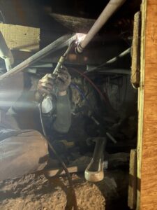 An HVAC technician working on piping in a confined space during a service call by KO HVAC Heating & Cooling in Kingston, PA.