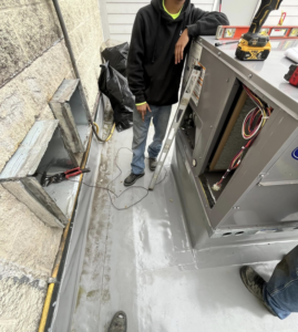 An HVAC technician performing service on a commercial rooftop unit for WV Heating and Air in Morgantown, WV