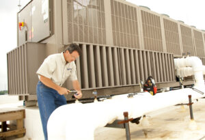 An HVAC technician performing work on large commercial rooftop HVAC units and piping for Climate Systems, Inc. in Sioux Falls, SD.