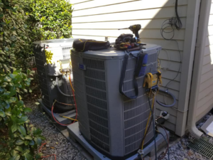 An HVAC technician working on two outdoor air conditioning units with tools at Comfort Zone A/C & Heating, LLC in Kenner, LA.