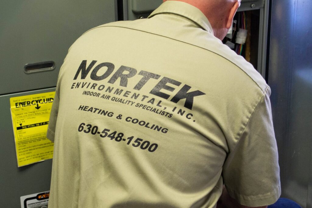 A Nortek Environmental, Inc. HVAC technician working on a heating and cooling unit in Naperville, IL.