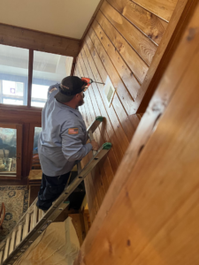An HVAC technician on a ladder working on a wall vent for Workman Mechanical in Graham, NC.