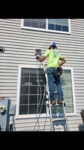 An HVAC technician on a ladder performing work on an outdoor unit for Naranjo Heating & Cooling Specialist Inc. in Joliet, IL.
