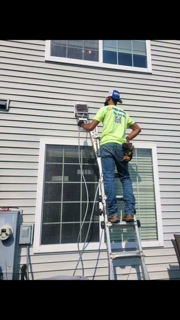An HVAC technician on a ladder performing work on an outdoor unit for Naranjo Heating & Cooling Specialist Inc. in Joliet, IL.