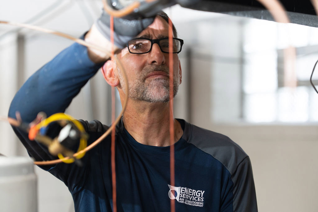 An HVAC technician working on the wiring of an indoor HVAC unit for Alan Energy Services in Naperville, IL