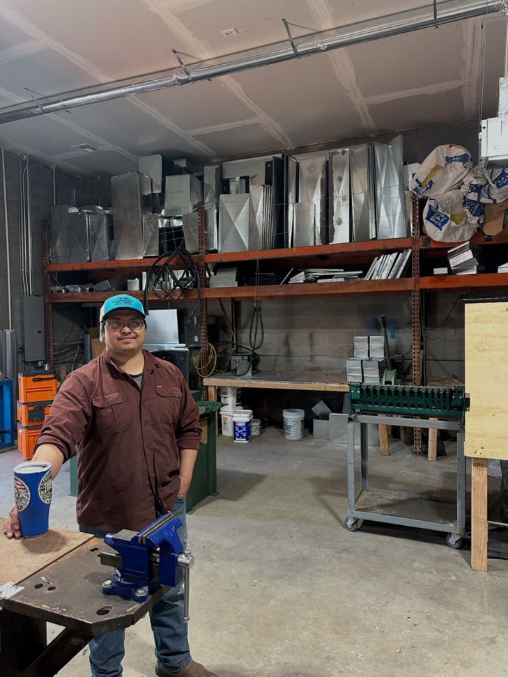 An HVAC technician in a workshop with ductwork components at Thompson Heating & Cooling in Page, AZ