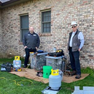 HVAC technicians performing AC service or repair with tools and refrigerant tanks for Roy Rogers Heating and Air in Indianapolis, IN.