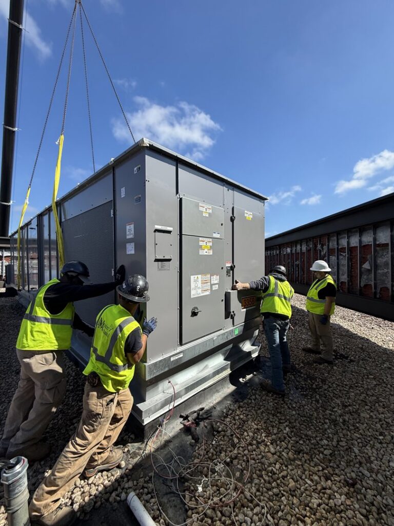 HVAC technicians adjusting a large commercial rooftop unit during installation by Modern Mechanical HVAC in Garner, NC.