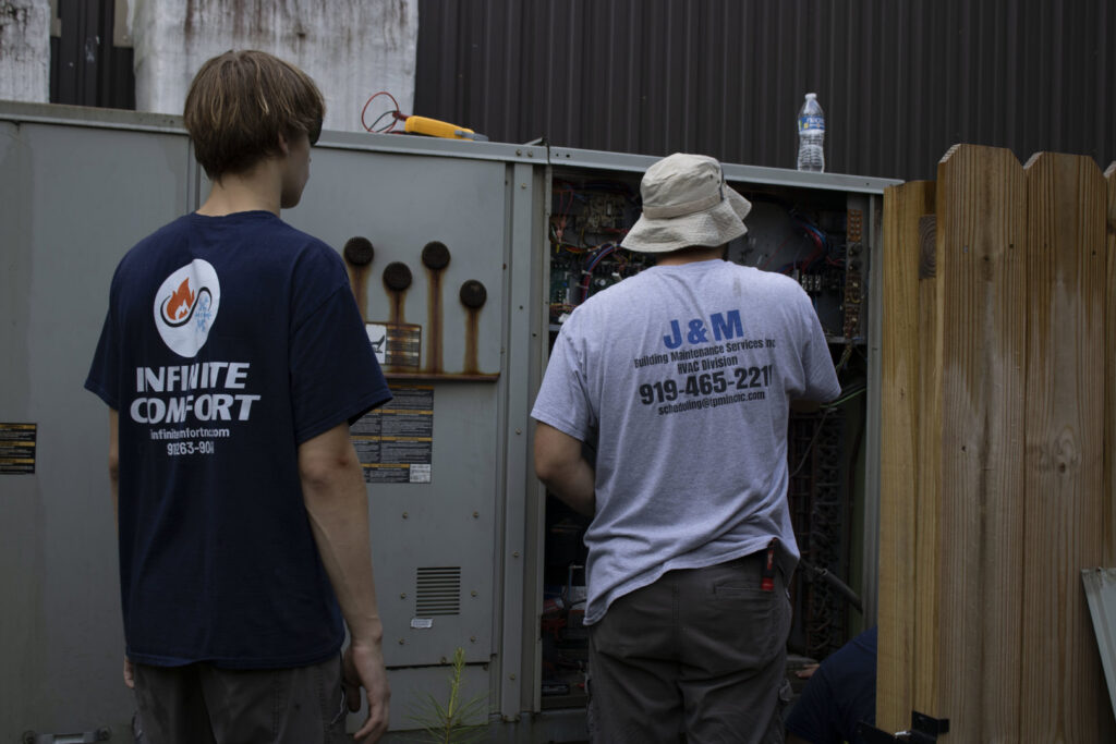 Infinite Comfort technicians working on a large commercial HVAC unit in Youngsville, NC.