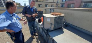 Two HVAC technicians discussing work on commercial rooftop units for Hurn Mechanical Heating & Cooling in El Cajon, CA.