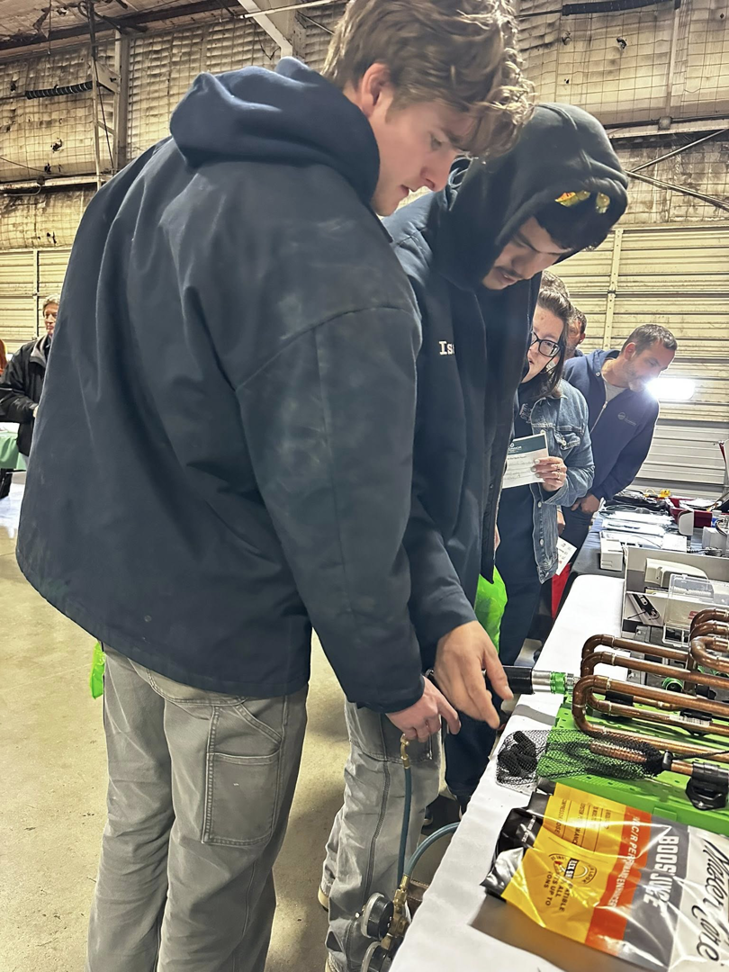 Two HVAC technicians examining copper piping and fittings at Specialized Service Heat & Air in Wichita, KS.