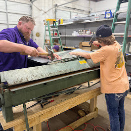 Two Milan Heating & Air technicians fabricating sheet metal ductwork in their workshop in Milan, TN.