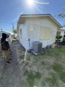 Two HVAC technicians from Gibson's Air Conditioning & Heating inspecting an outdoor AC unit at a residential property in Corpus Christi, TX.