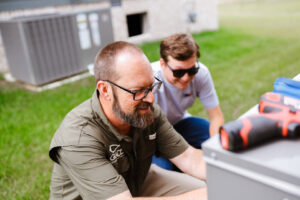 Two HVAC technicians inspecting an outdoor air conditioning unit together for Grace Heating & Air in Clarksville, TN.