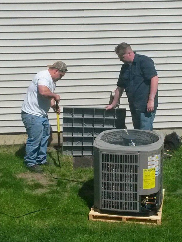 Two HVAC technicians installing an outdoor air conditioning unit for a client at Affordable Services Heating and Air Conditioning Inc. in Aurora, IL
