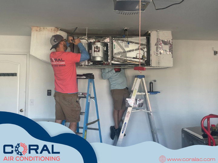 Two HVAC technicians from Coral Air Conditioning installing an air handler unit in a garage in Cape Coral, FL.