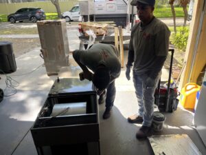 Two HVAC technicians installing an air handler unit in a garage for Timely Air Conditioning in Riverview, FL.
