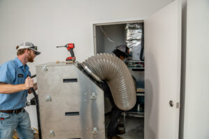 Bob Woodall Air Care Systems technicians installing air quality equipment connected to an HVAC system in Dothan, AL.