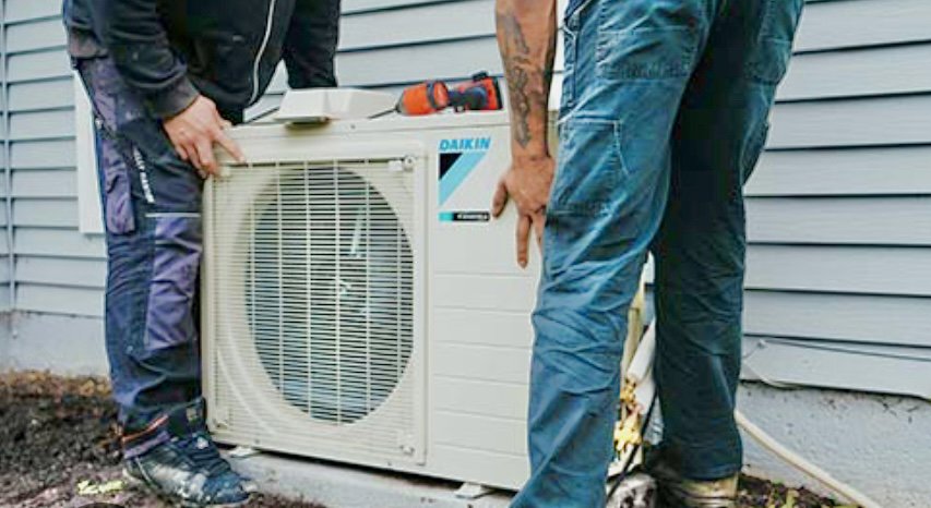 Two HVAC technicians installing an outdoor Daikin air conditioning unit for DND Mechanical in Columbus, OH.