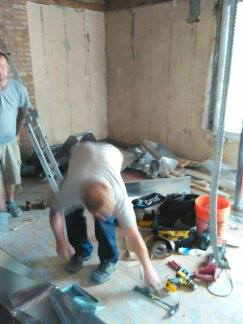 Two HVAC technicians installing new ductwork on a job site for All Pro HVAC Expertise in Columbus, OH.