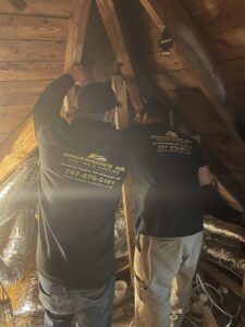 Two HVAC technicians installing or repairing ductwork in an attic for Anderson's Air in Newport News, VA