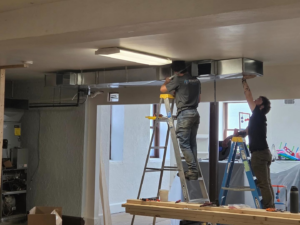 Two HVAC technicians installing new ductwork in a ceiling for Berkshire Heating and Cooling in Pittsburgh, PA