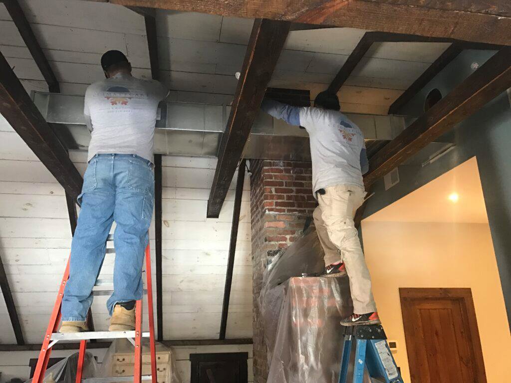 HVAC technicians installing new ductwork in a residential ceiling by Climate Care Heating & Air Conditioning in Norwalk, CT