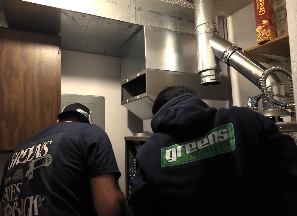 Two HVAC technicians from Greens Heating & Air Conditioning installing ductwork and furnace in Douglasville, GA.
