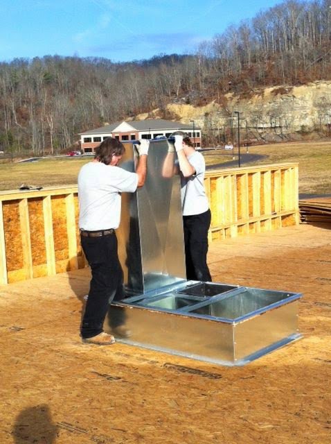 Two HVAC technicians installing sheet metal ductwork on a rooftop construction site for KATS Heating & Cooling in La Grange Park, IL.