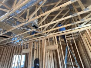 Two HVAC technicians installing ductwork in the ceiling of a new construction home for Dewees HVAC in Conway, AR.