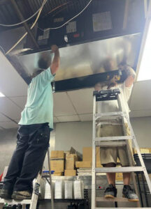 Two HVAC technicians installing or repairing overhead ductwork for T&D Air Conditioning in Fort Lauderdale, FL.