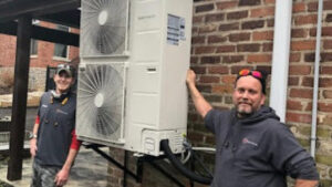 Two HVAC technicians installing a mini-split system on a brick wall for Aces of Air Inc. in Georgetown, KY.