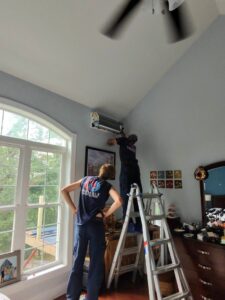 Two HVAC technicians installing an indoor mini-split unit in a bedroom for Variable Comfort Solutions in Huntington, WV.